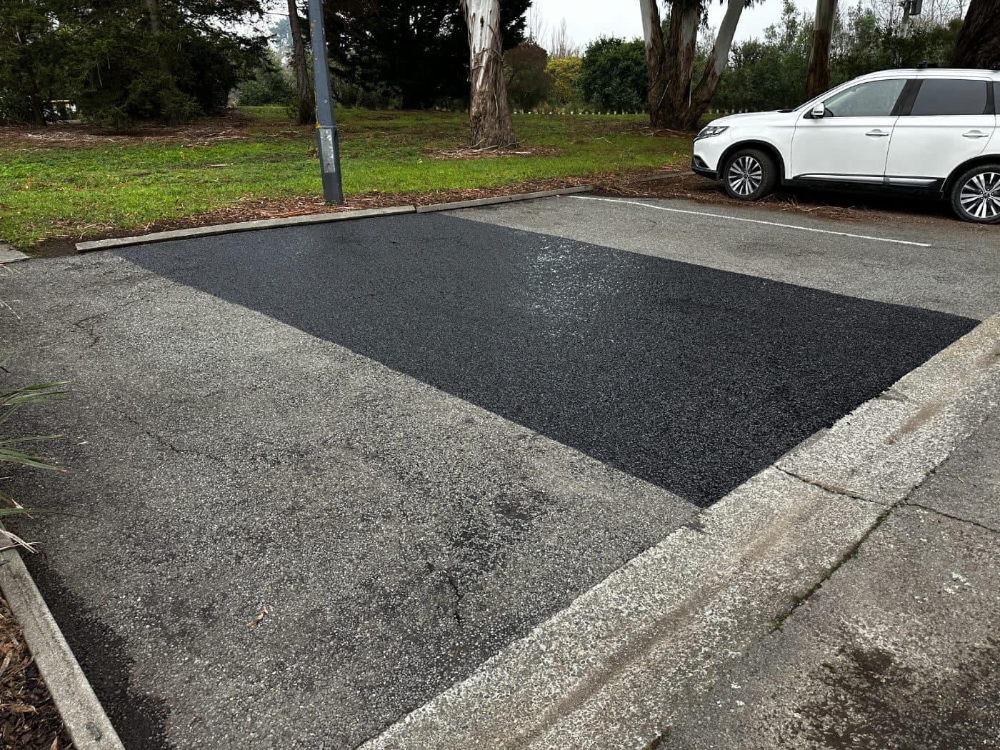 A single rejuvenated car park bay beside faded asphalt