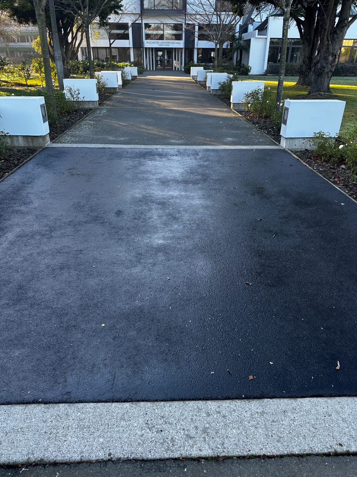 Freshly rejuvenated asphalt path leading to a building