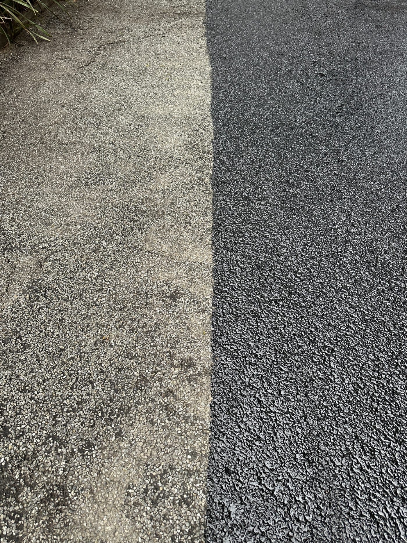 Old faded asphalt beside freshly rejuvenated asphalt, up close